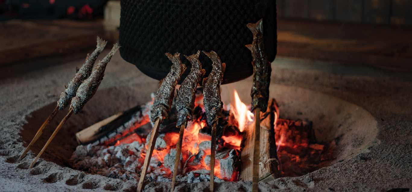 昔ながらの囲炉裏の薪火でじっくりと焼く、岩魚の塩焼きのイメージ